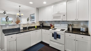 A modern kitchen with white cabinetry, a black countertop, a stove, a microwave, and a ceiling fan. - Waterfront, Harbourside, Water Park, Beach, #3318 (Indian Rocks Beach)