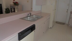 Una cocina con un lavaplatos doble, lavavajillas y refrigerador.