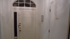 Una puerta blanca con una pequeña ventana y un timbre.