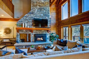 Una sala de estar acogedora con chimenea de piedra, televisor de pantalla plana y asientos cómodos.