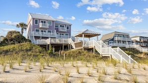 A beachfront property with multiple buildings, including a large house with a balcony and a smaller structure with a roof. - The Pinnacle - OCEANFRONT Home.  Amazing Views, Pool, Hot Tub, 2 Kitchens,
Deck (Emerald Isle)