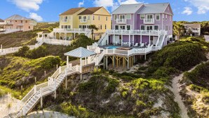 A beachfront property with multiple colorful houses, a swimming pool, and a wooden deck. - The Pinnacle - OCEANFRONT Home.  Amazing Views, Pool, Hot Tub, 2 Kitchens,
Deck (Emerald Isle)