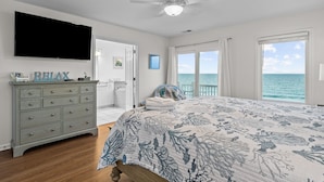 A bedroom with a bed, a dresser, a ceiling fan, a TV, and a view of the ocean. - The Pinnacle - OCEANFRONT Home.  Amazing Views, Pool, Hot Tub, 2 Kitchens,
Deck (Emerald Isle)