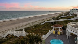 A beachfront property with a swimming pool, a beach access walkway, and a pier in the background. - The Pinnacle - OCEANFRONT Home.  Amazing Views, Pool, Hot Tub, 2 Kitchens,
Deck (Emerald Isle)