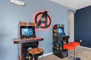 Two arcade machines with a large Avengers logo on the wall behind them.