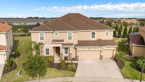 A two-story residential building with a front driveway, a garage, and a well-maintained lawn. - Huge, Popular Resort Villa 30+ Guests - Resort/Pool/Spa/Game Room/ Near Disney! (Davenport)