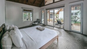 Een slaapkamer met een groot bed, een plafondventilator en uitzicht op het buiten.