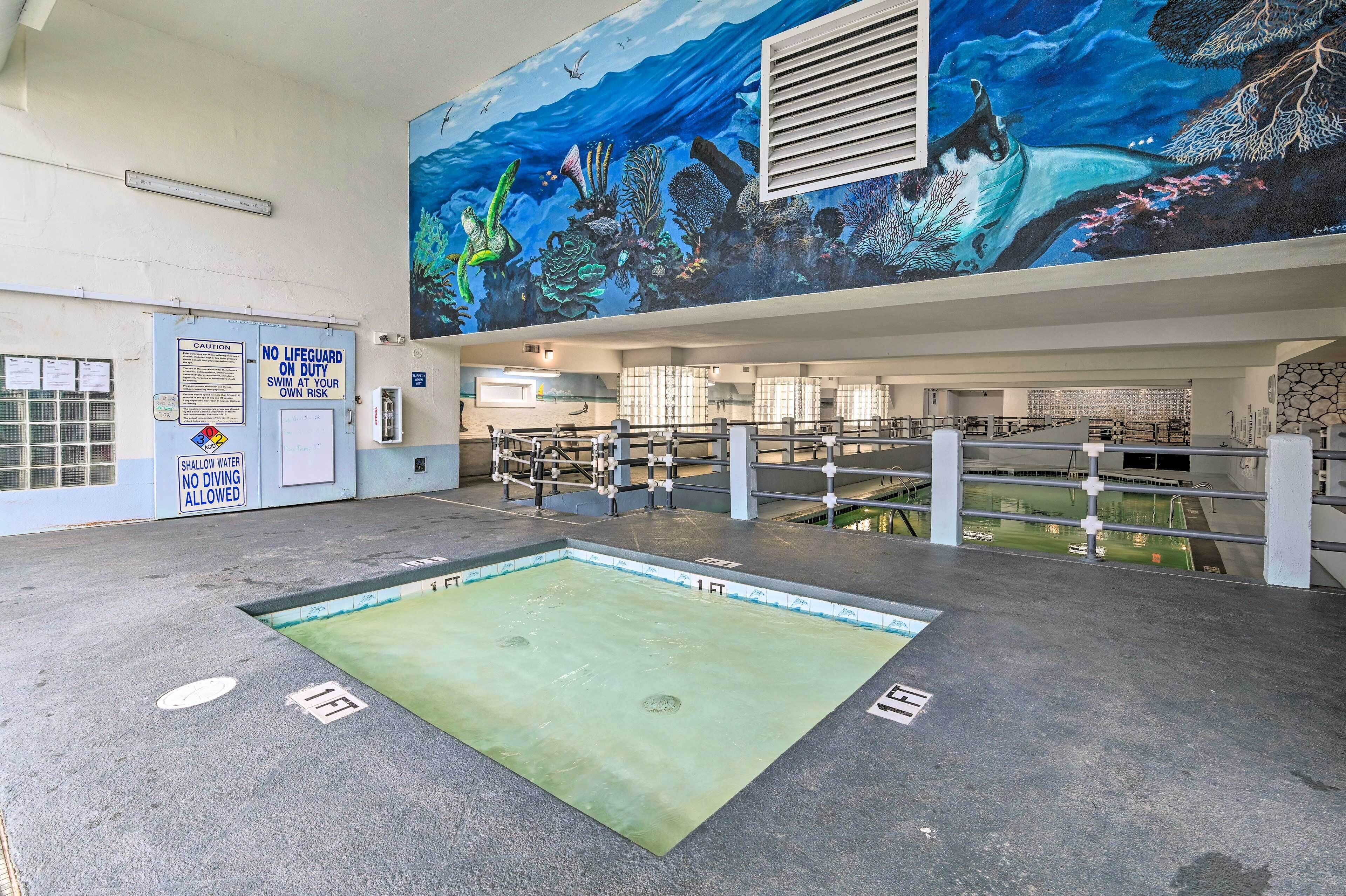 An indoor swimming pool with a mural of underwater scenery on the wall, a lifeguard station, and a sign indicating no diving allowed.