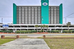 A hotel with a prominent green and white color scheme, featuring a large sign with the hotel's name. There is a parking structure in front, and the hotel appears to have multiple floors with a uniform exterior design. - Murrells Inlet Condo w/ Ocean Views & Pool Access! (Murrells Inlet)