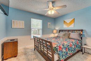 A bedroom with a bed, a nightstand, a dresser, a ceiling fan, and a window with blinds.