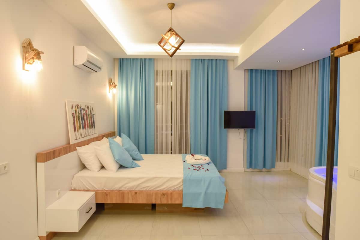 A modern bedroom with a wooden bed, a flat-screen TV, and a built-in jacuzzi.