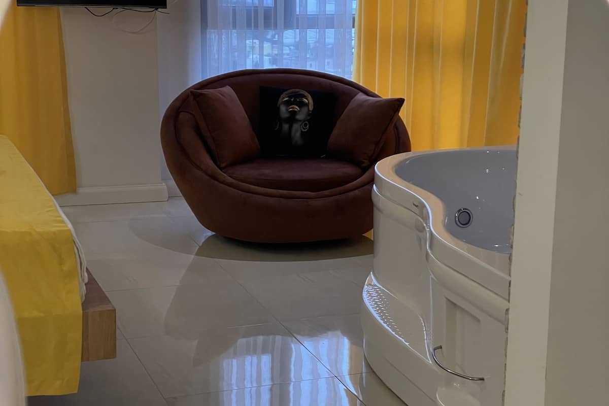 A modern room with a sofa, a bathtub, and a TV mounted on the wall.