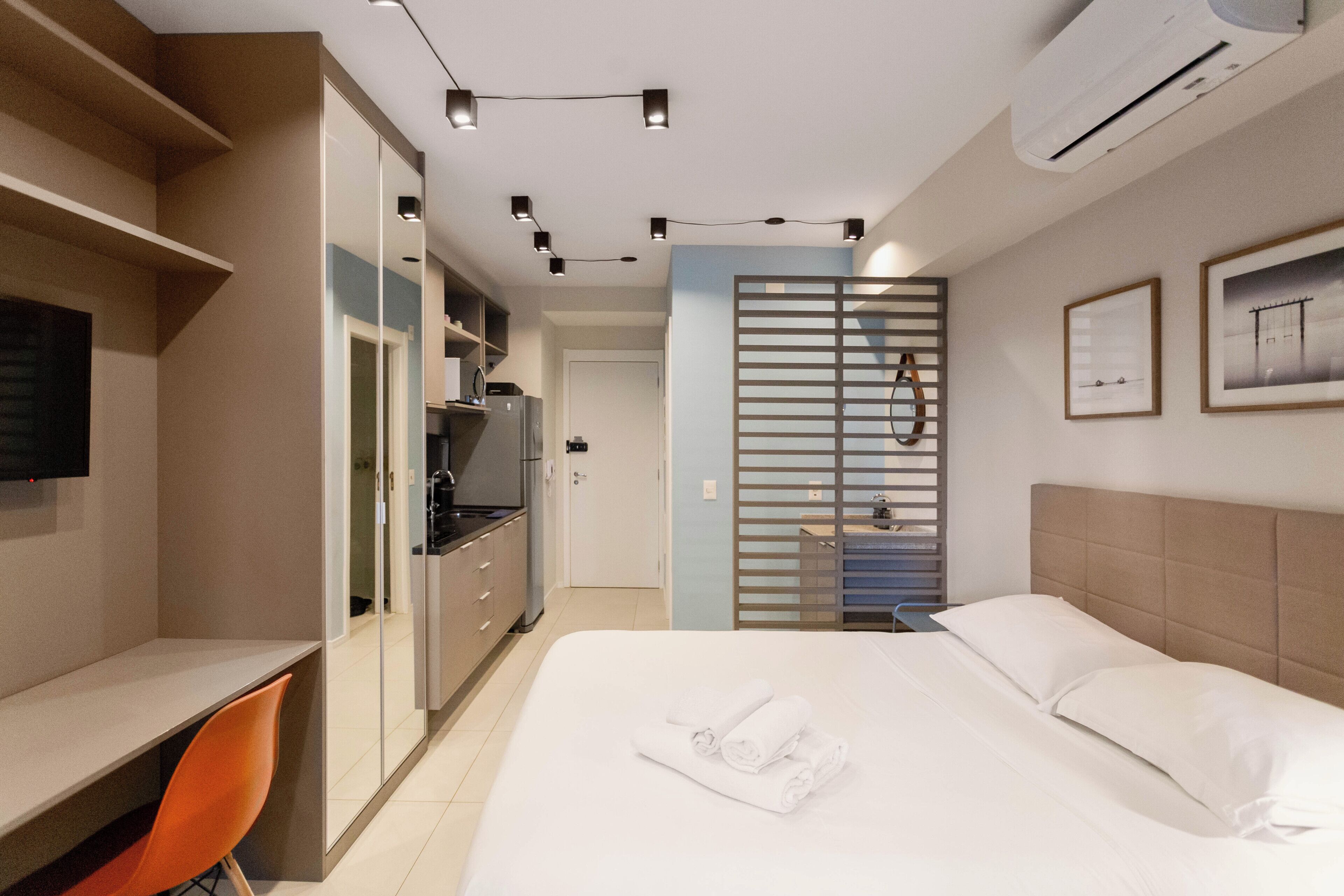 Une chambre d’hôtel équipée d’un lit, d’un bureau, d’une chaise, d’une télévision et d’une kitchenette.