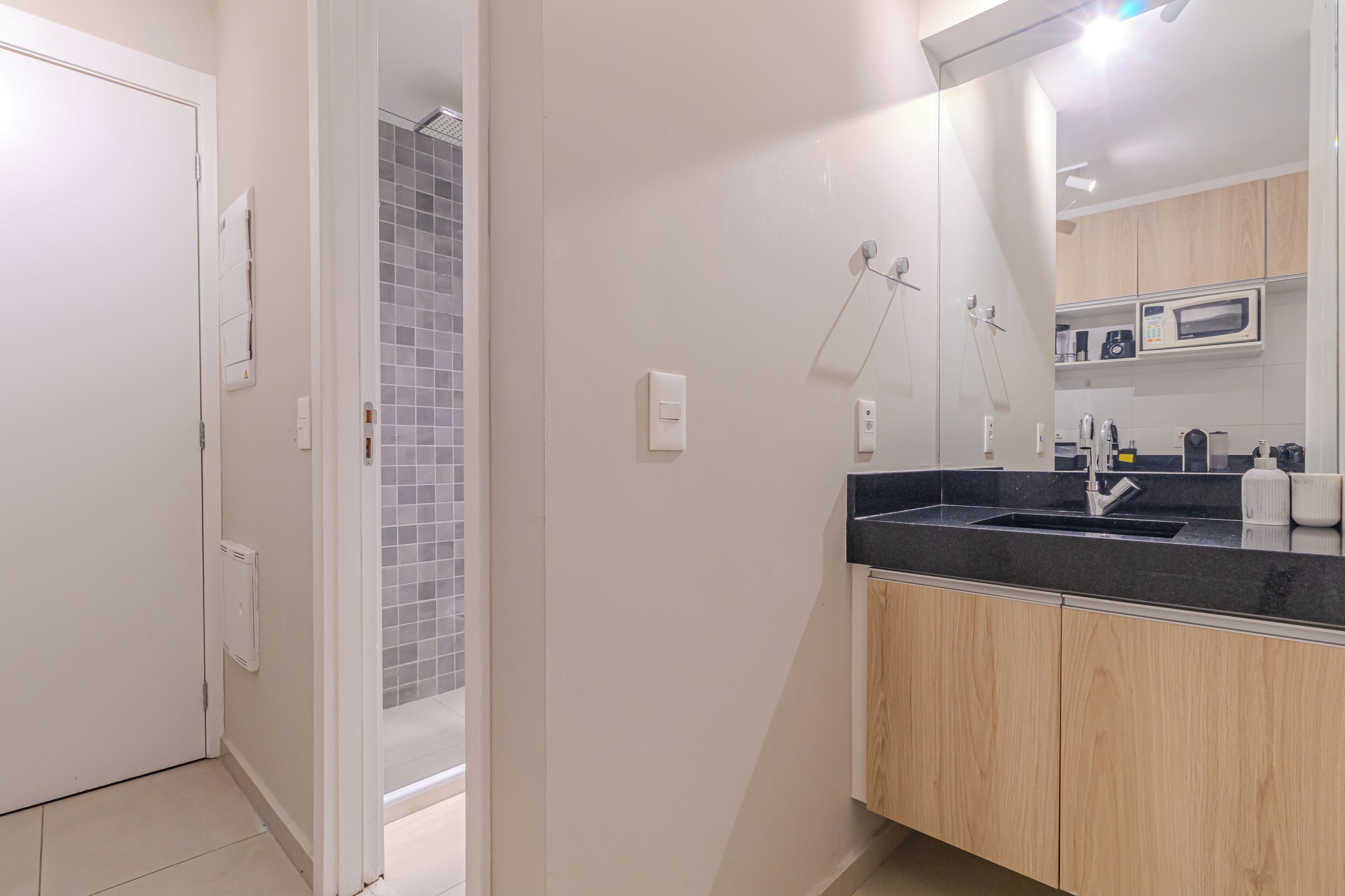 A modern bathroom with a shower, a sink with a black countertop, and wooden cabinets.