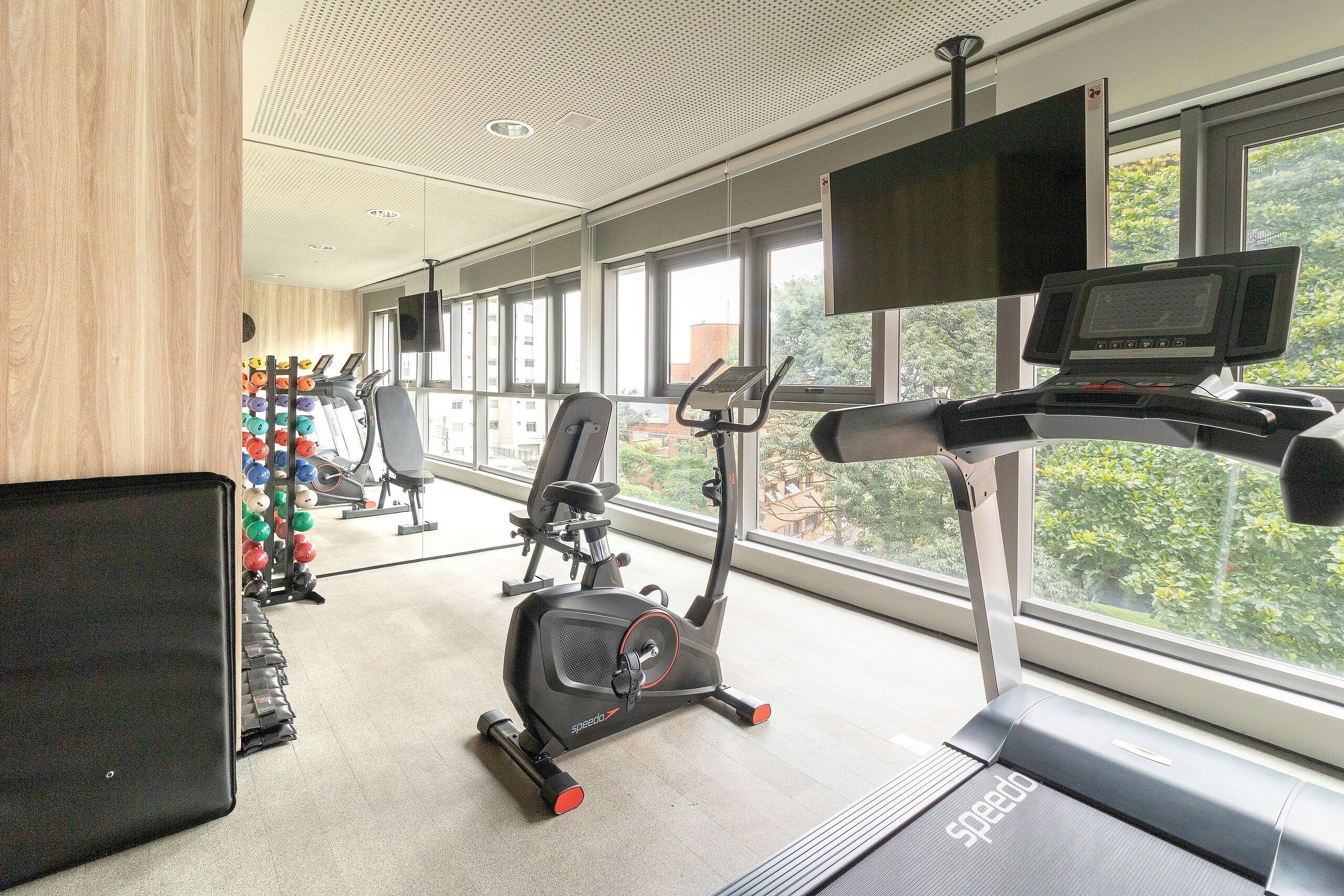 Un gimnasio con cintas de correr, bicicletas estáticas y una máquina de remo.