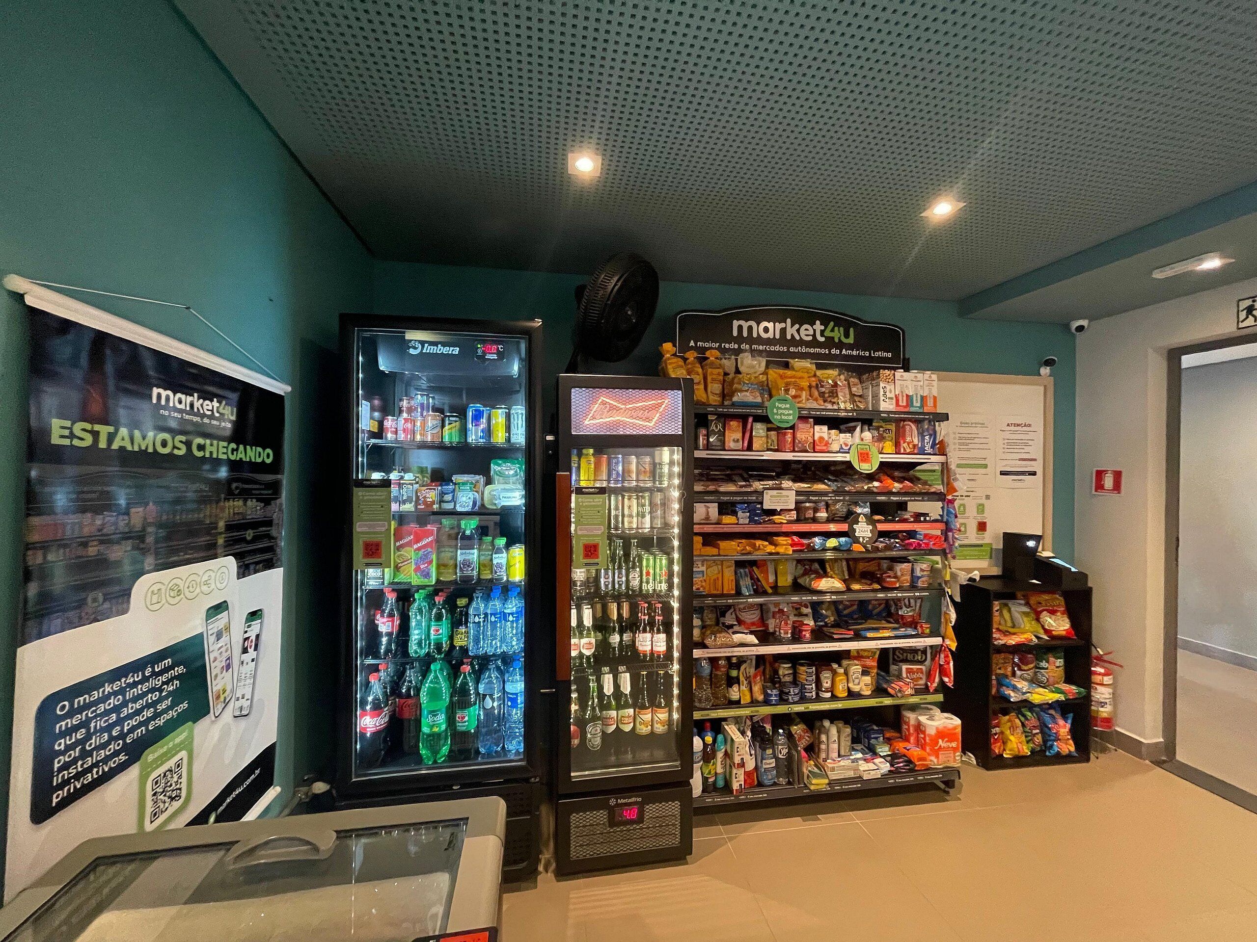 Un área de quioscos de autoservicio con dispensadores de bebidas, una sección refrigerada y estantes llenos de bocadillos y bebidas.