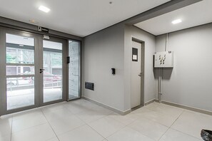 Ein modernes Interieur mit Glastür, einer kleinen Tür und einem Stromkasten an der Wand.