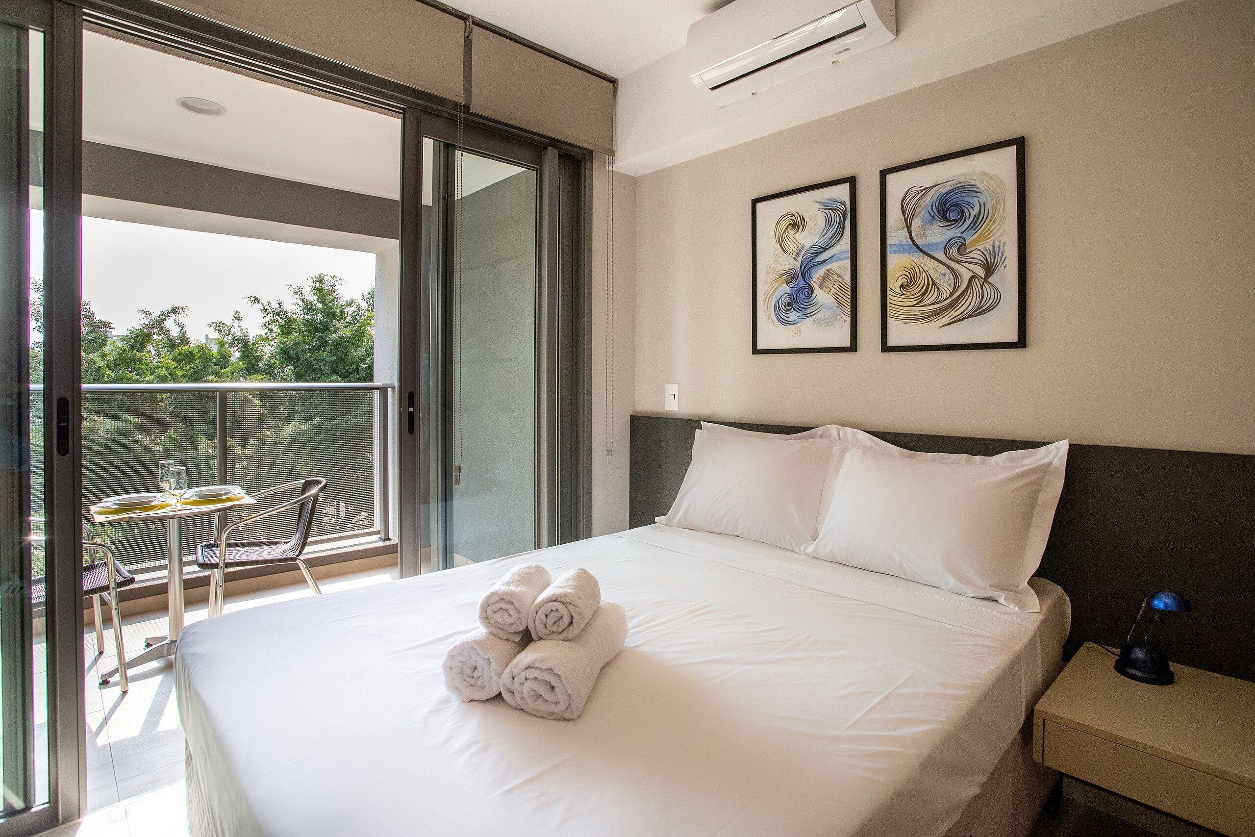 Ein Hotelzimmer mit Bett, Nachttisch, Schreibtisch mit Stuhl und Balkon mit Tisch und Stühlen.