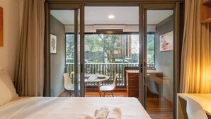 Habitación de hotel con cama, balcón con mesa y sillas, y vistas al exterior.