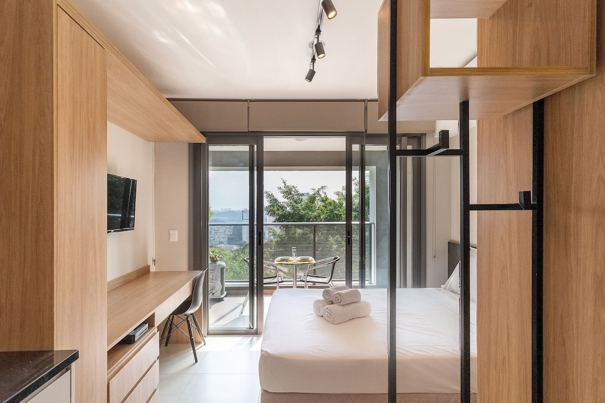 Un dormitorio moderno con una cama grande, un escritorio y un balcón con mesa y sillas.