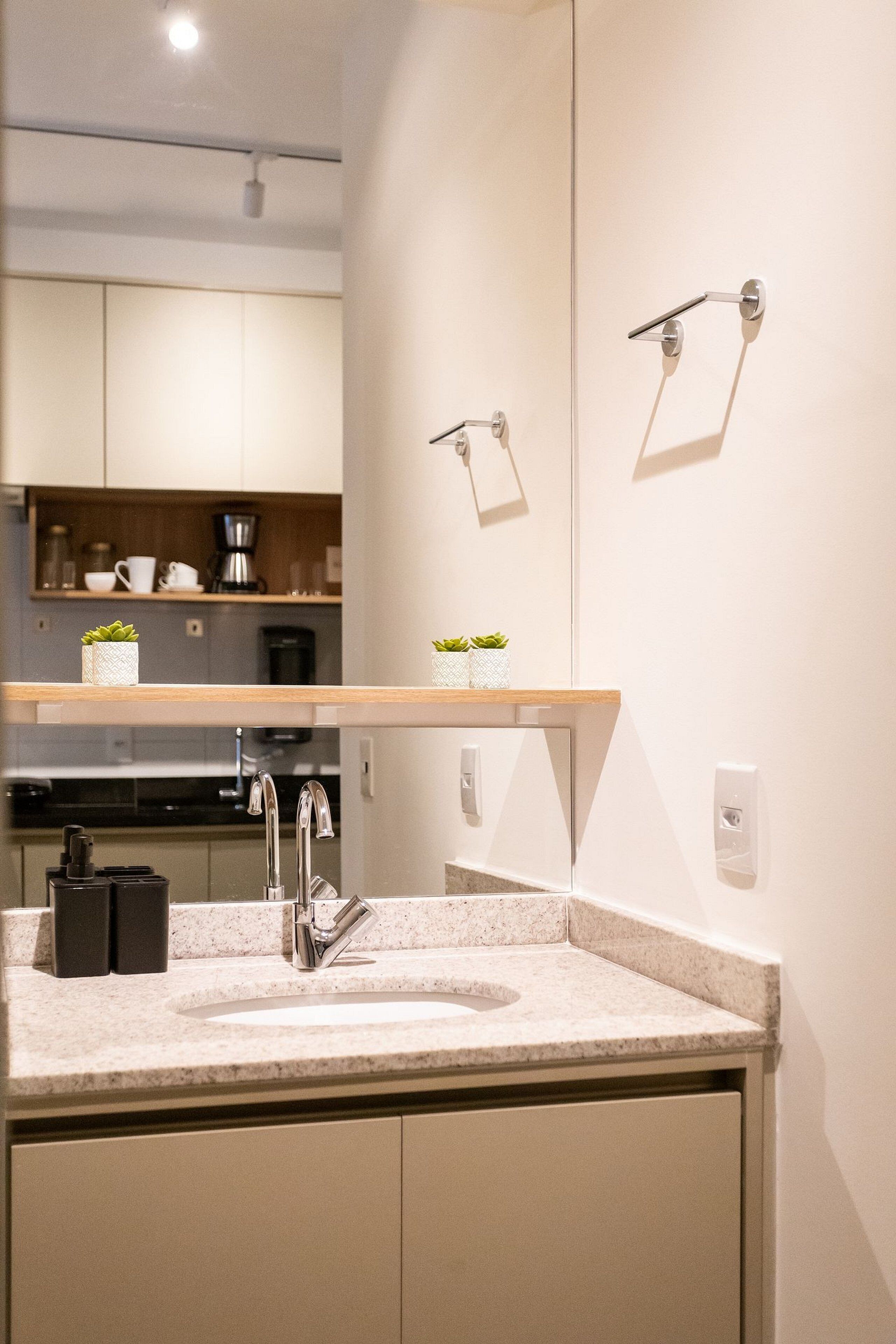 A modern bathroom with a sink, mirror, and towel rack.