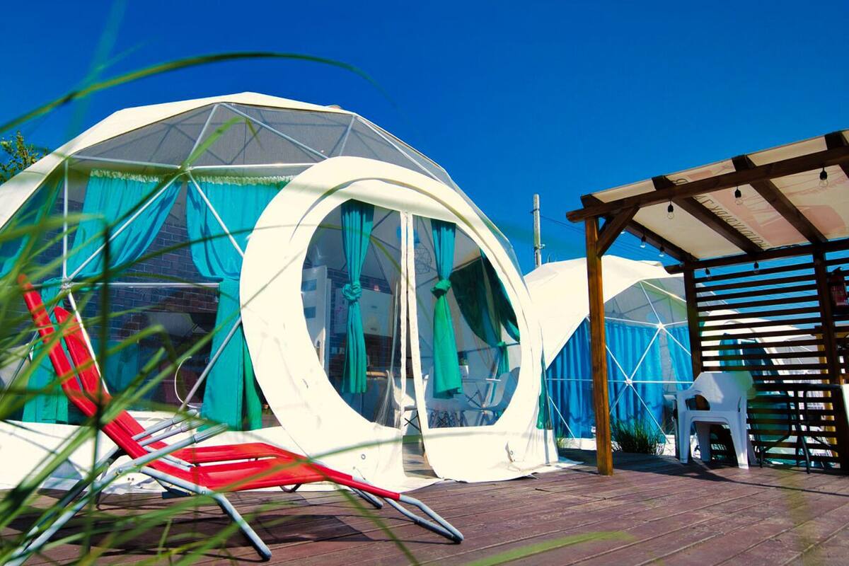 Une structure en forme de dôme, dotée de grandes fenêtres et d’une terrasse en bois.