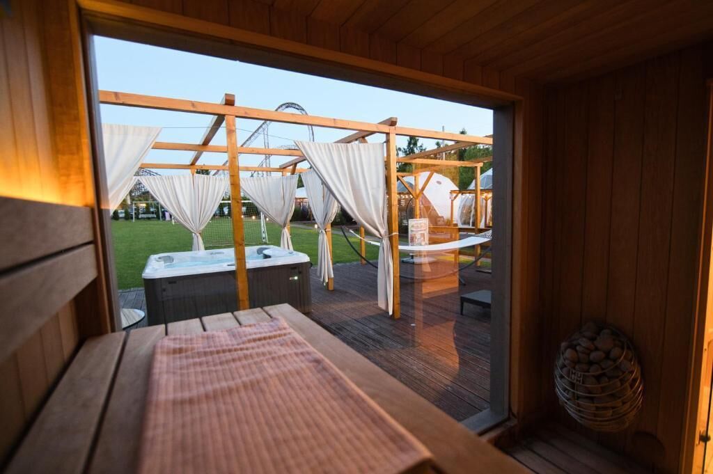 A wooden deck with a hot tub and a covered seating area.