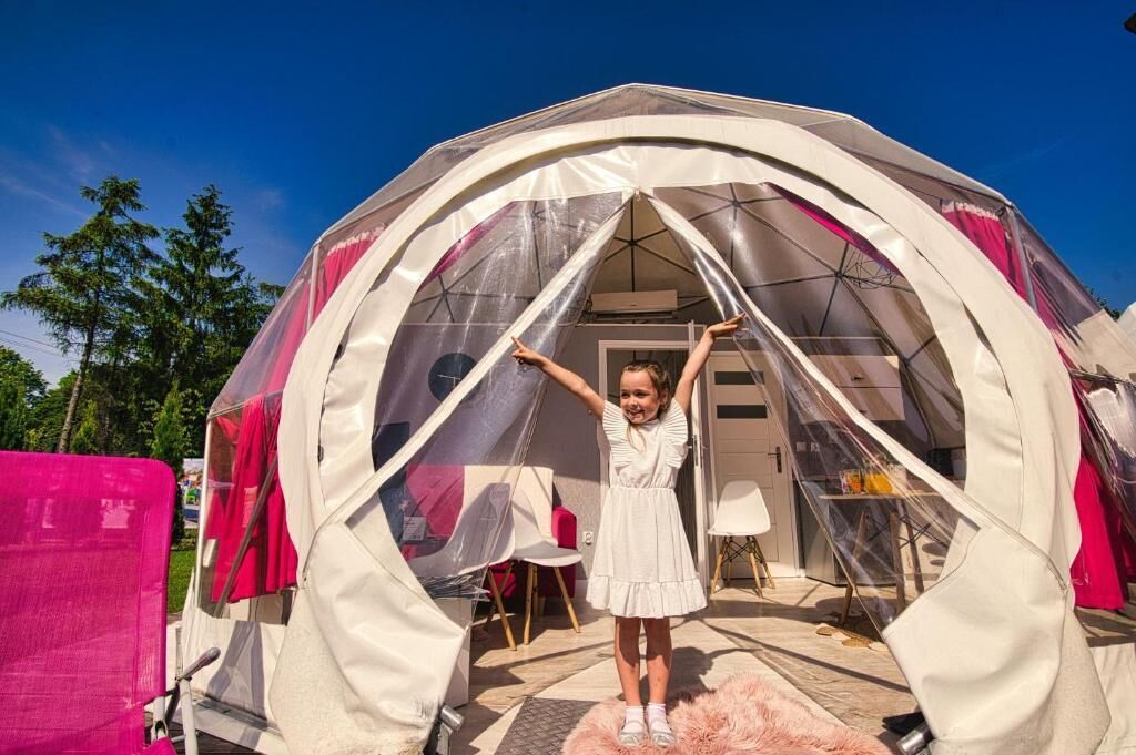 A dome-shaped tent with a clear entrance, a small table, and chairs inside.