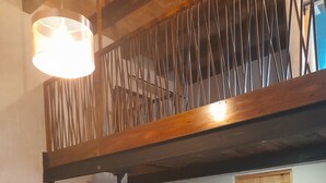 Un dormitorio con una escalera de madera, una cama con colcha estampada y una puerta de madera.