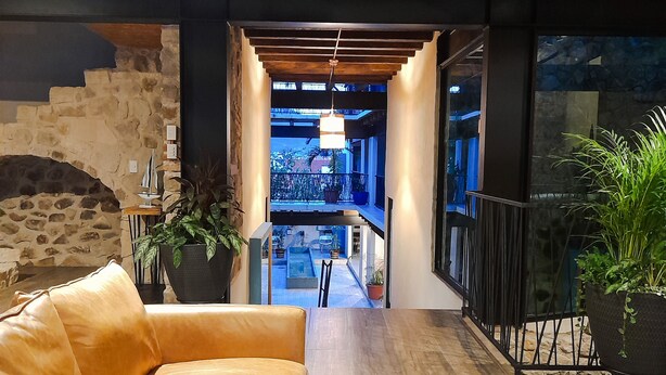 Un interior moderno con un sofá de cuero, paredes de piedra y vistas a un balcón exterior.
