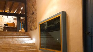 Una escalera de madera lleva a una zona de recepción con paredes de piedra y una puerta azul.
