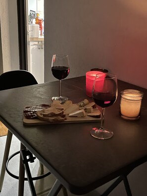 Une table avec une planche à fromages, deux verres de vin rouge, une bougie allumée et un chandelier.