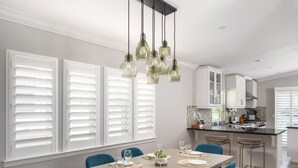 Un espace repas avec une longue table dressée pour six personnes, entourée de chaises bleues.