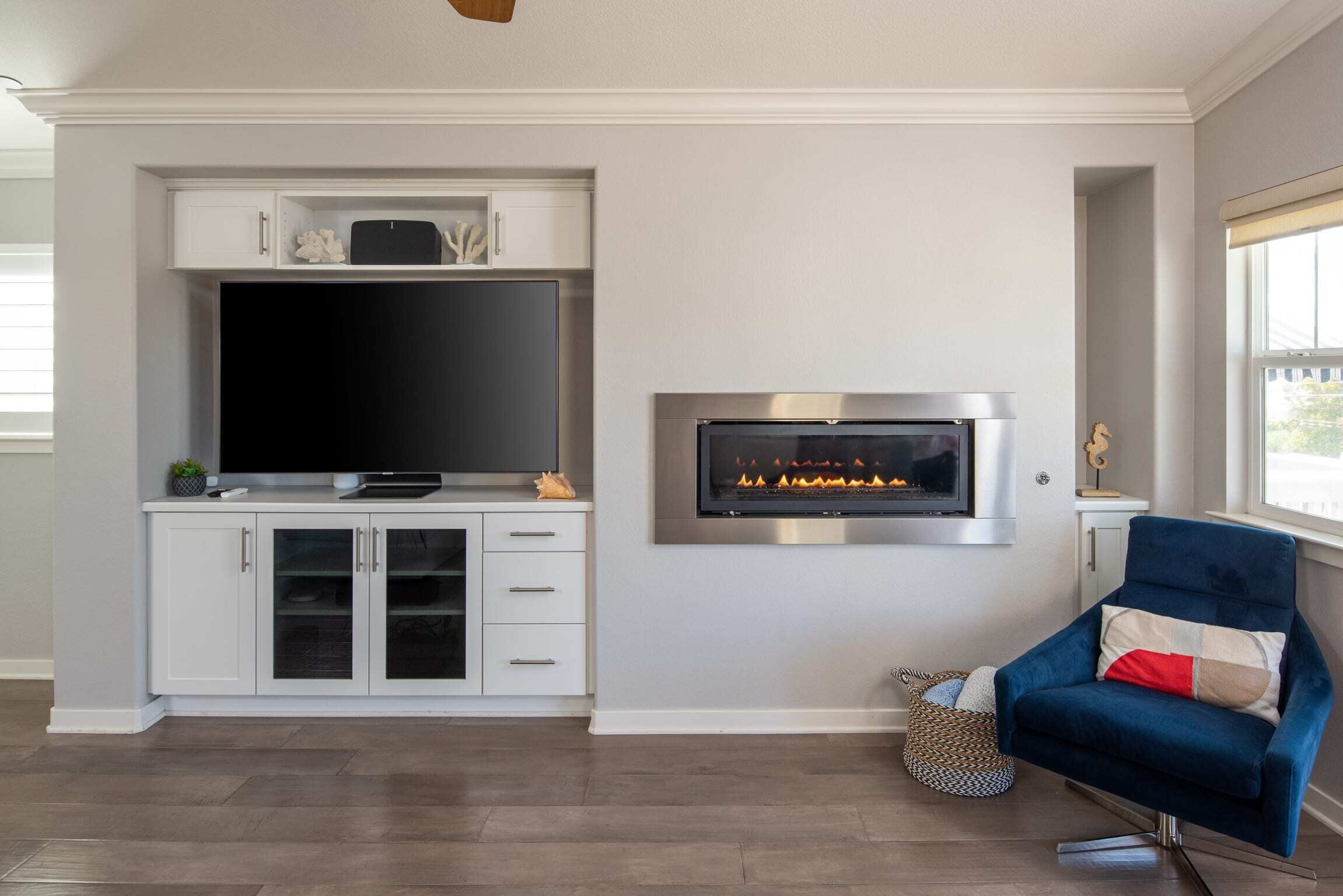 Una sala de estar moderna con una televisión de pantalla plana, una chimenea y un sillón azul.