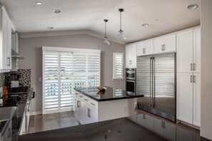 Una cocina moderna con gabinetes blancos, electrodomésticos de acero inoxidable y encimera negra.