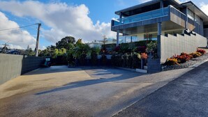 Una moderna casa a due piani con un balcone, immersa in un giardino curato e dotata di vialetto lastricato.