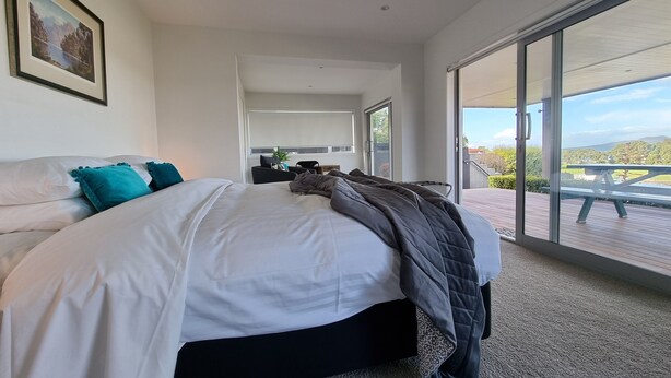 Una camera da letto moderna con un letto grande, una scrivania e vista su un terrazzo e il paesaggio.
