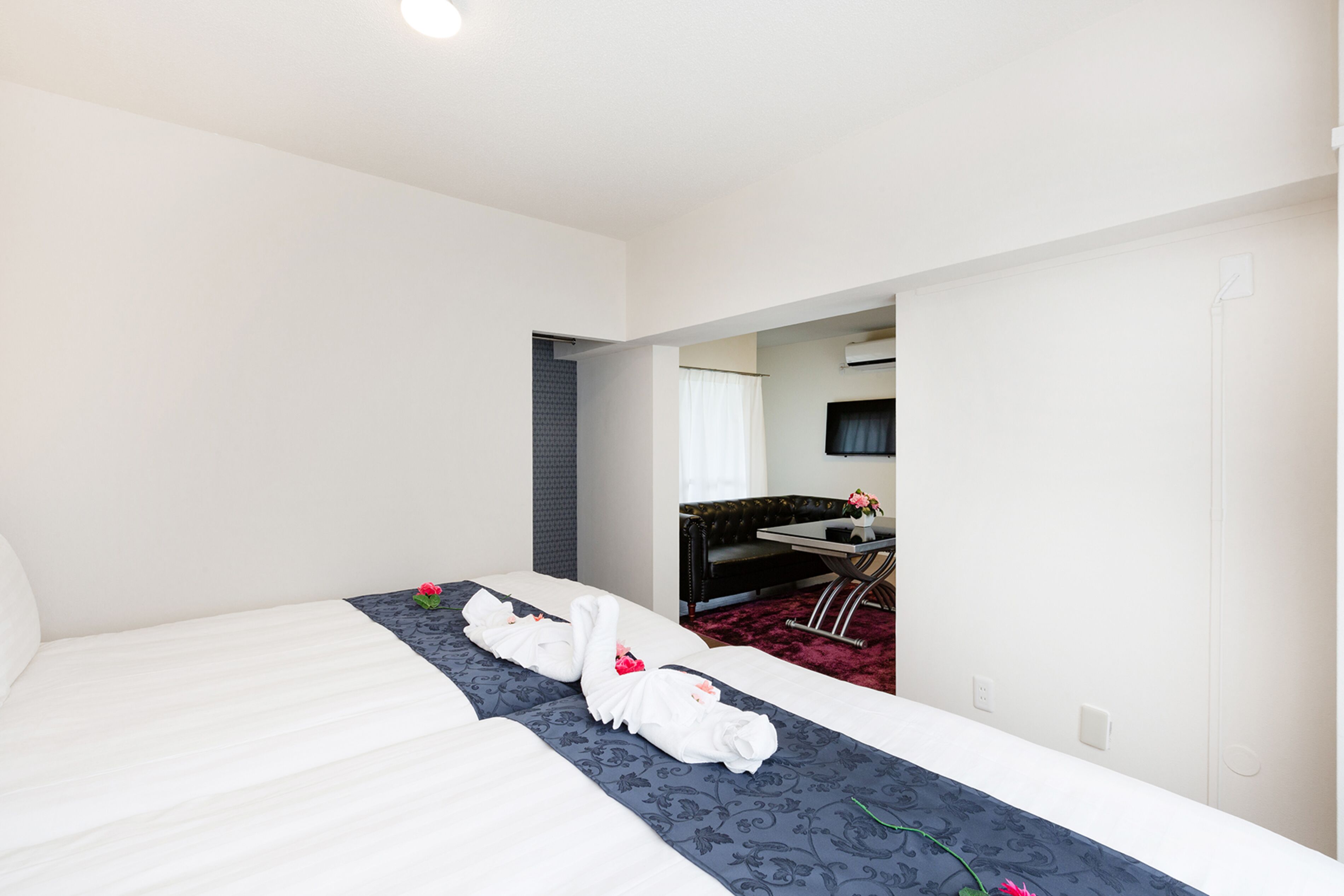 Ein Hotelzimmer mit einem großen Bett, einem kleinen Schreibtisch und einer separaten Sitzecke mit einer Couch und einem Fernseher.