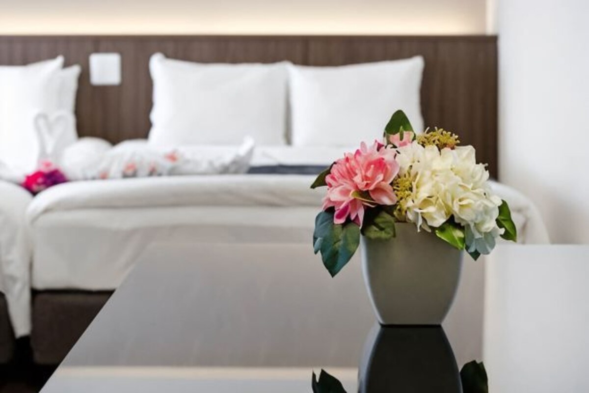 Una habitación de hotel con una cama bien hecha, un jarrón con flores y un diseño moderno.