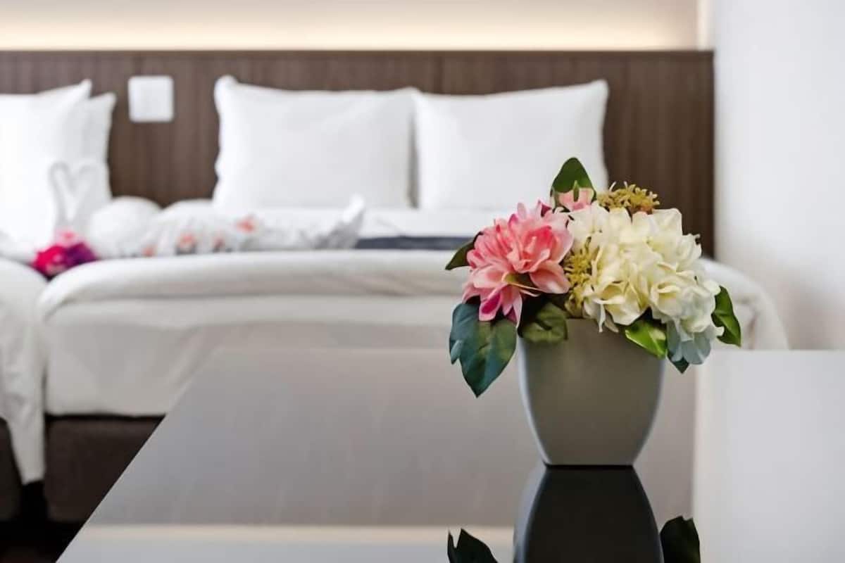 A hotel room with a neatly made bed, a vase with flowers, and a modern design.