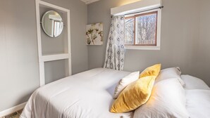 Un dormitorio con cama, ventana con vistas, espejo y aire acondicionado de pared.