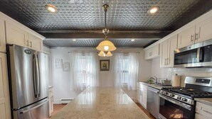 Una cocina moderna con electrodomésticos de acero inoxidable, una isla central y un techo oscuro.