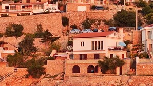 Un edificio costero con fachada de piedra, varios balcones y techo rojo.