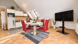 Een compacte keuken met een eethoek, inclusief een tafel met stoelen, een flatscreen televisie en een plafond met dakramen.