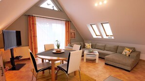 A cozy loft apartment with a dining area, a sofa, and a TV. - Apartment Jonathan - Modern equipped apartment near the center! (Zingst)