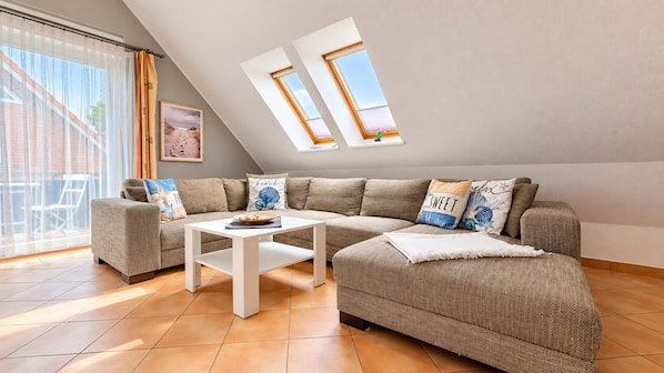 A modern living room with a sectional sofa, a white coffee table, and two skylights.