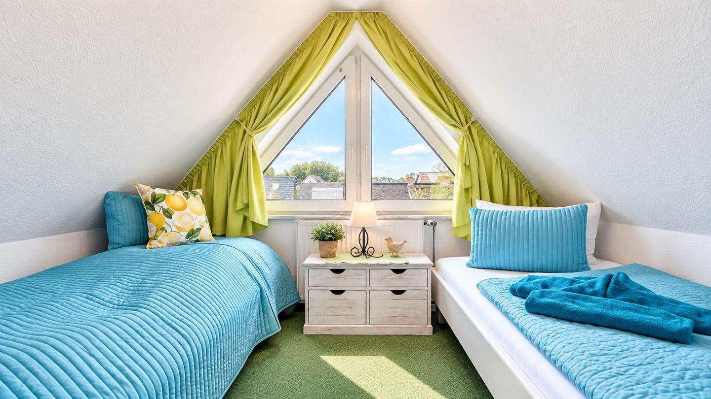 Une chambre avec deux lits, une fenêtre avec des rideaux, une table de chevet avec une lampe et une petite plante.