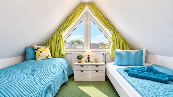 A bedroom with two beds, a window with curtains, a bedside table with a lamp, and a small plant. - Apartment Jonathan - Modern equipped apartment near the center! (Zingst)