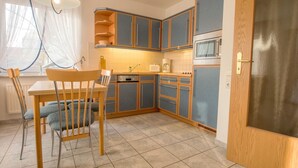 Une cuisine compacte avec des meubles bleus, un four à micro-ondes et un coin repas comprenant une table et des chaises.