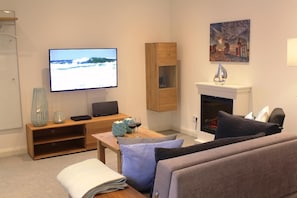Ein Wohnzimmer mit Fernseher, Kamin und einer Couch.